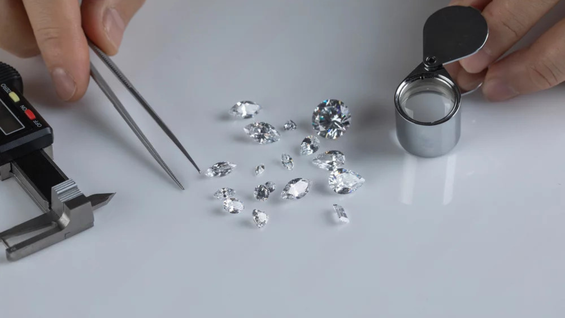 Diamond appraisal process with tweezers, loupe, and diamond scale on a white surface