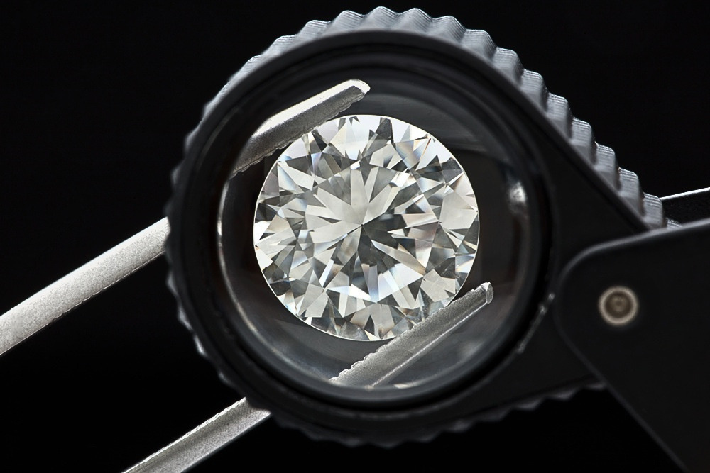 Round brilliant cut diamond viewed through a jeweller’s loupe, illustrating visual diamond grading and evaluation techniques taught in the Canadian Diamond Academy’s online diamond course.