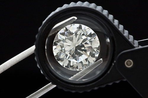 Round brilliant cut diamond viewed through a jeweller’s loupe, illustrating visual diamond grading and evaluation techniques taught in the Canadian Diamond Academy’s online diamond course.