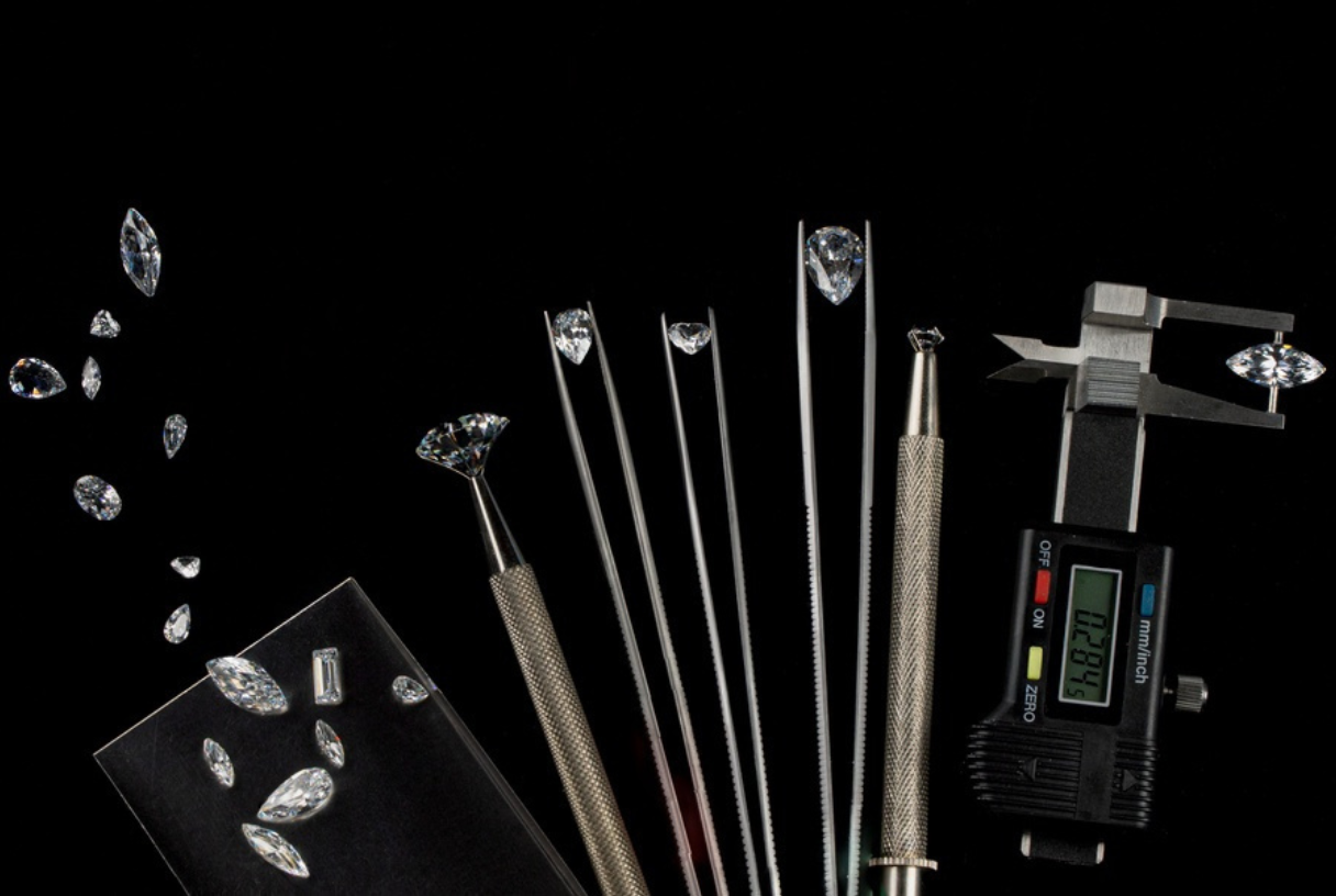 Loose cut diamonds and gemological tools used for diamond grading and measurement — tweezers, gem‑setting probe, and digital caliper measuring a marquise‑cut diamond on black background. Perfect for jewelry appraisal, diamond education, and gemstone precision equipment.