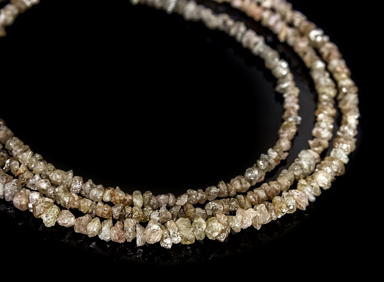 Close-up of a string of rough diamond beads on a black background